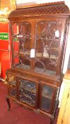 A Chippendale Revival walnut display cabinet fitted glazed panel doors with carved detail above
