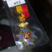 A Belgium Cross medal on original silk ribbon decorated with blue and green enamel