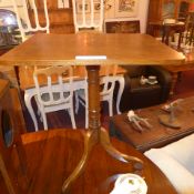 A C19th oak tilt top table raised on turned column and tri form supports