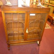 An oak bookcase fitted pair of glazed panel doors and raised on turned stretchered supports