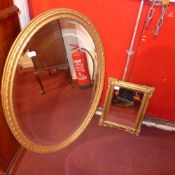 An early C20th looking glass with oval bevelled plate in carved gilt wood frame and a smaller