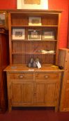 An old pine dresser the raised open shelved upstand above the two drawers with cup handles and