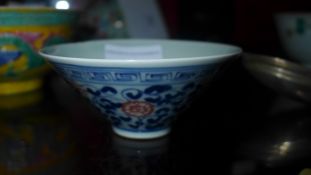 A Chinese bowl of small size glazed with flowers and vines in red and blue