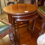 A mahogany nest of three oval low tables on stretchered supports and castors