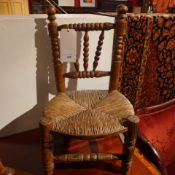 A childs pine chair with rush seat (one stretcher missing)