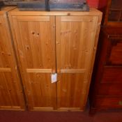 A contemporary pine side cabinet with pair of panel doors enclosing shelves