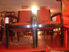 A pair of vintage barbers chairs upholstered in red faux leather