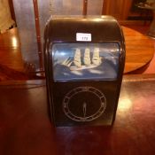 A 1930s bakelite mantle clock with mechanically animated and illuminated model of a ship on the high