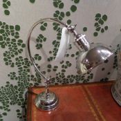 A pair of nickel plated desk lamps with overhanging shades on circular bases in working order