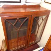 A mahogany display cabinet fitted two astragal galzed panel doors enclosing adjustable shelves on
