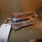 A silver plated butter dish with engraved detail and twin handles