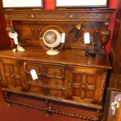 An oak sideboard with carved and panelled upstand supported by bulbous supports and fitted three