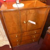 An Art Deco walnut tall boy fitted pair of panel doors above drawers and raised on slender reeded