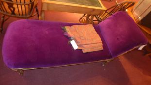 An antique chase longue, upholstered in purple velour with an ornate giltwood frame raised on carved