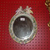 A C19th Meissen porcelain table mirror the oval plate within flower encrusted frame with cherub