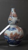 A Chinese double gourd shaped vase decorated with landscape reserves in blue and orange