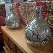 A pair of glass and silvered bottles of large size with foliate decoration
