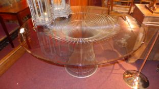 A contemporary William Planter circular dining table having a bevelled glass top raised on a