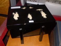 A Japanese black lacquered box with bone and mother pearl figures of Geisha and birds applied raised