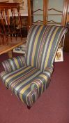 A double scroll arm armchair upholstered in stripy fabric on tapering supports