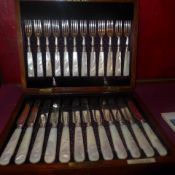 An oak cased complete set of twelve hallmarked silver fruit knives and forks with mother of pearl