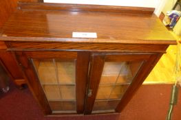 An oak bookcase with pair of leaded glazed panel doors enclosing shelves