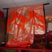 A Japanese red silk wedding kimono with irridescent thread decorated with cranes on a black