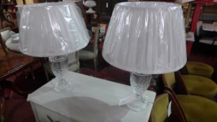 A pair of cut glass table lamps with white silk shades