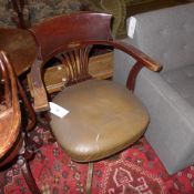 A 1940`s oak chair upholstered in brown leather and raised on swivel supports