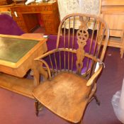 A C19th elm windsor elbow chair with pierced wheel and stick back above solid seat raised on