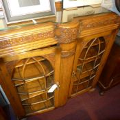 A carved oak bookcase fitted two glazed panel doors enclosing shelves on turned feet