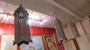 A set of four wrought metal hexagonal form hanging lanterns with extensive pierced detail