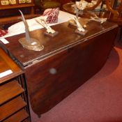 A George III mahogany drop flap dining table raised on reeded supports