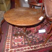 A George III oak occational table the circular top raised on turned column and tripod supports