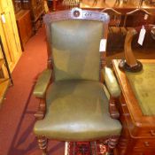 A Victorian carved mahogany armchair upholstered in green leather and raised on turned supports