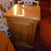 A Victorian pine washstand with rising lid revealing basin above single panel door