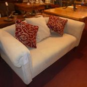 A double scroll arm two seater sofa upholstered in ivory mottled fabric and with extra cushions on