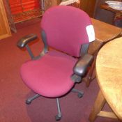 A Herman Miller desk chair upholstered in maroon fabric on adjustable swivel supports
