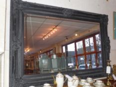 A rectangular wall mirror of large size the bevelled plate within black painted and ornately