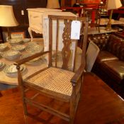 A fruitwood childs elbow chair with a caned seat on turned stretchered supports