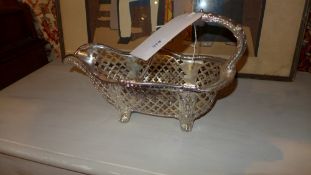 A silver plated basket form wine cradle with pierced detail on scrolling feet