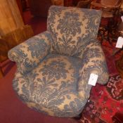 A double scroll armchair upholstered in gold and blue foliate fabric