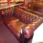 A Chesterfield two seater sofa upholstered in buttoned burgundy leather