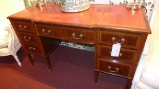 An Edwardian mahogany breakfront desk with tooled leather top above arrangement of seven drawers