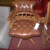 A mahogany Captains chair upholstered in brown buttoned leather on swivel supports
