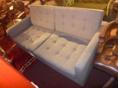 A contemporary designer two seater sofa upholstered in buttoned grey fabric raised on chromed