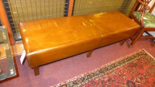 A tan hide leather upholstered bench of elongated form and raised on splayed supports
