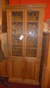 A pine side cabinet fitted pair of glazed panel doors above a further pair of cupboard doors