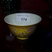 A Chinese cup of small size glazed yellow and decorated with dragons in relief