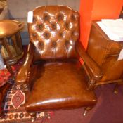 A Howard style armchair upholstered in buttoned tan leather and raised on turned supports and